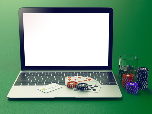 jeu de cartes et jetons de casino déposé sur un ordinateur portable